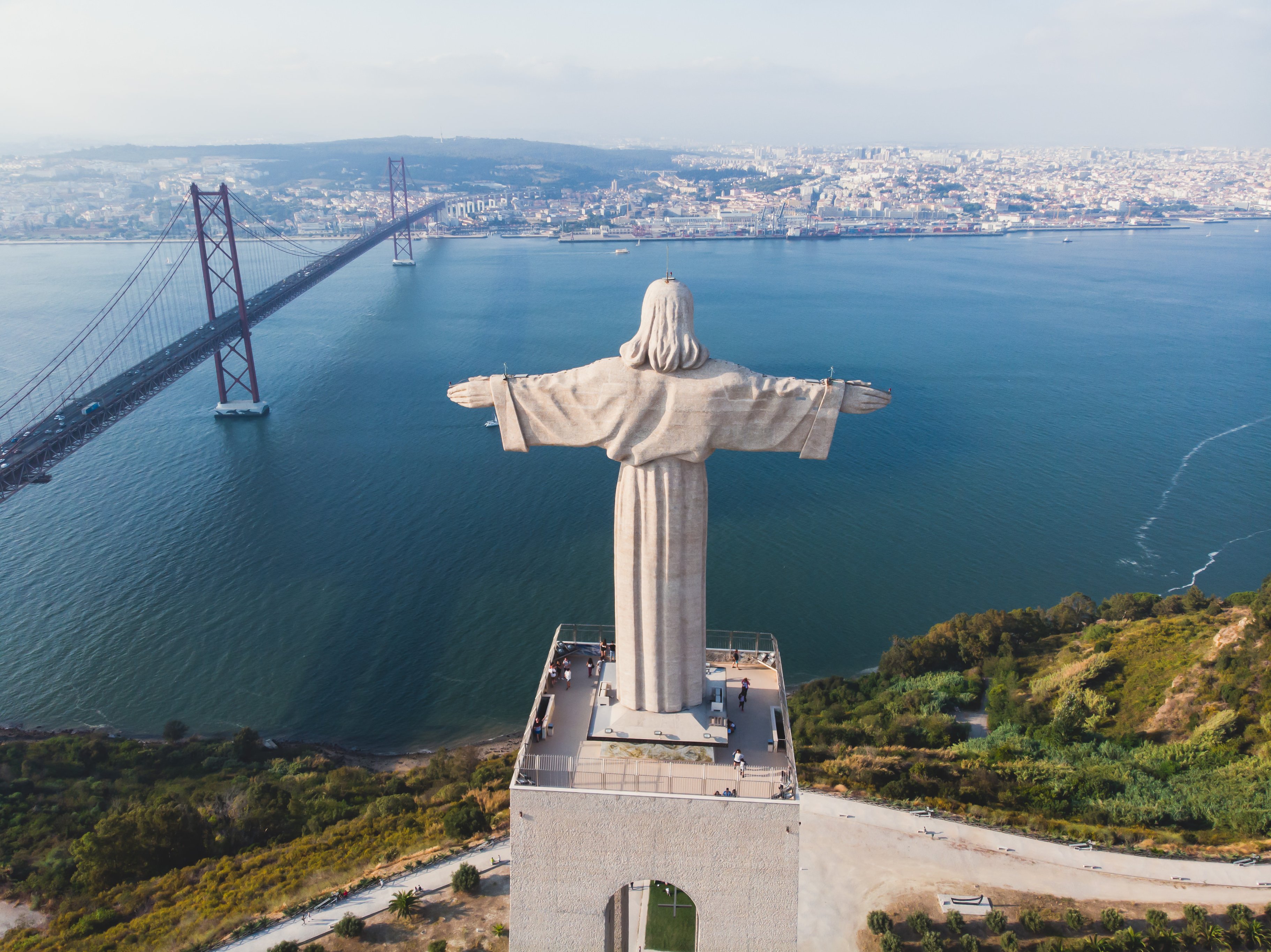 View of The Sanctuary of Christ the King, Cristo Rei, Almada, Lisbon, with 25 de Abril Bridge suspension Bridge, Tagus river, aerial drone view in summer sunny day